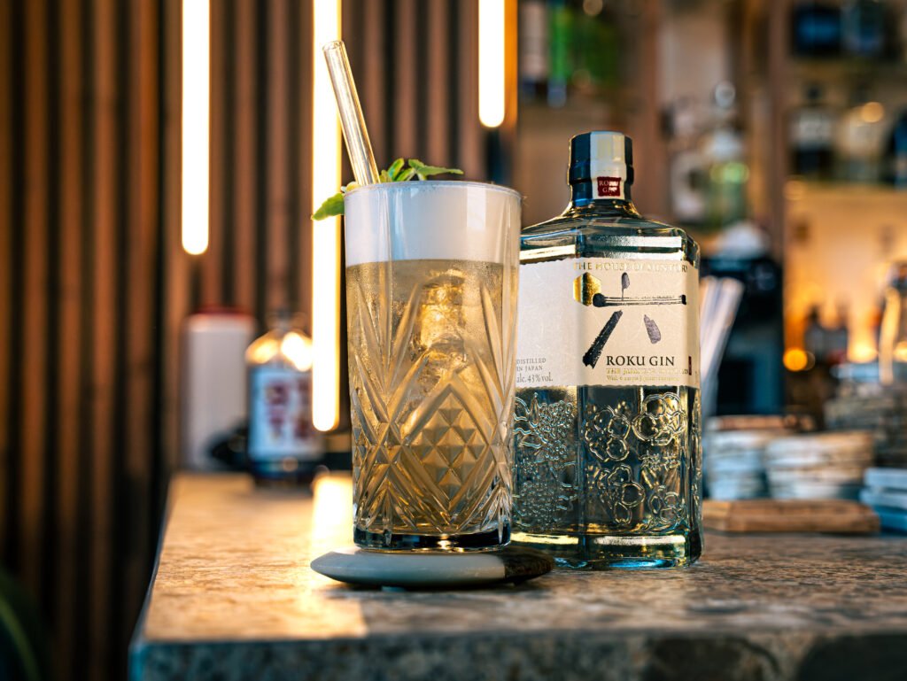 Cocktail dans un grand verre texturé avec une bouteille de Roku Gin