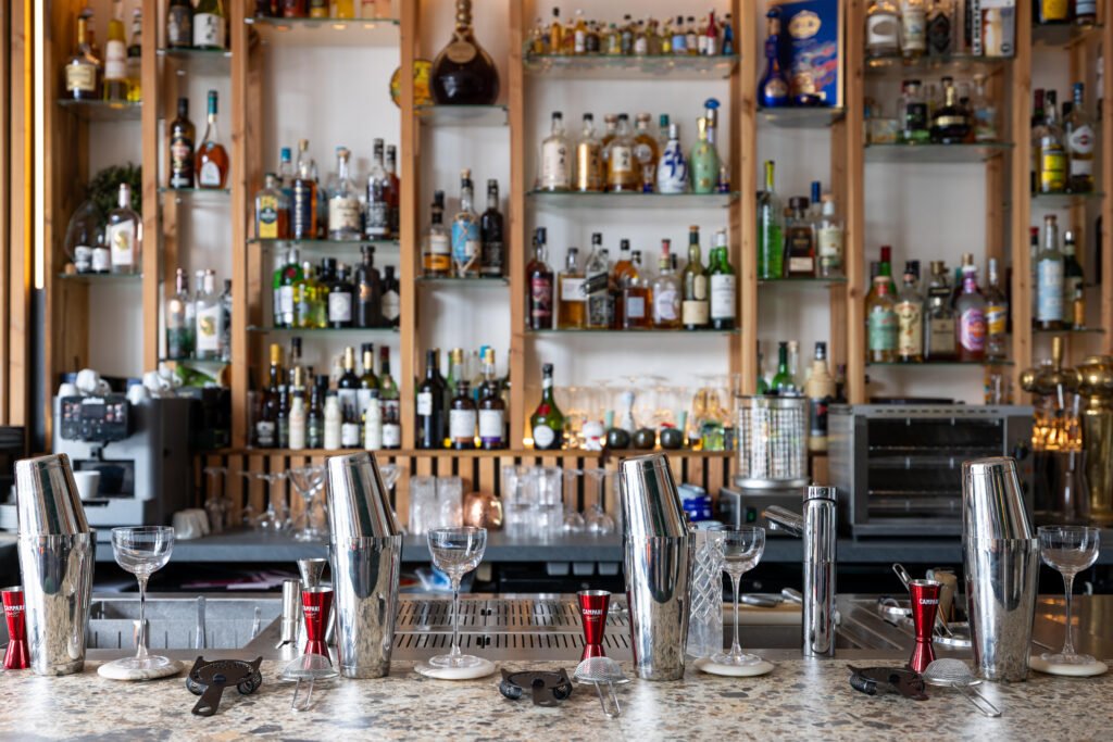 Wecandoo_Alexis-Perrichon_33_Cocktails_25082026-30 Comptoir de bar équipé avec shakers et étagères de bouteilles en arrière-plan